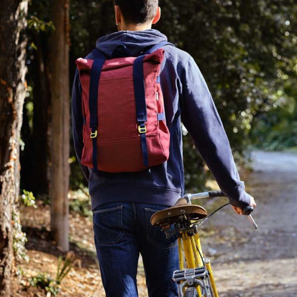 man with a bike wearing red recycled roll top backpack